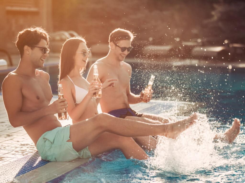 2 men + 1 woman drinking by pool