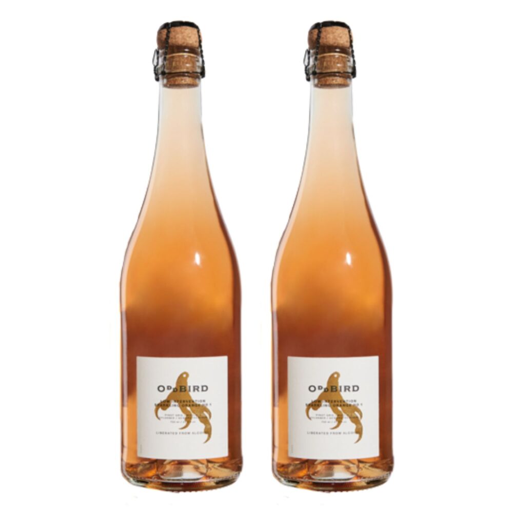 Two bottles of Oddbird Sparkling Orange non-alcoholic wine standing side by side with cork tops and golden-orange hue