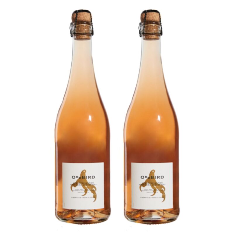 Two bottles of Oddbird Sparkling Orange non-alcoholic wine standing side by side with cork tops and golden-orange hue